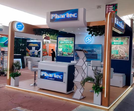 Un stand de feria para Phar-tec con señalización de marca, expositores de productos, material de marketing, zonas para sentarse y plantas decorativas.