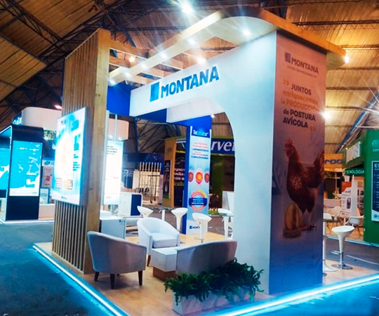 Stand de exposición para Montana con zonas para sentarse, pancartas promocionales y una estructura de exposición en un espacio interior bien iluminado.