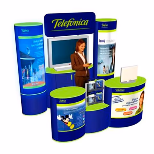 Una mujer en un stand azul y verde de Telefónica con carteles, una pantalla de televisión, mostradores y estanterías con material promocional.